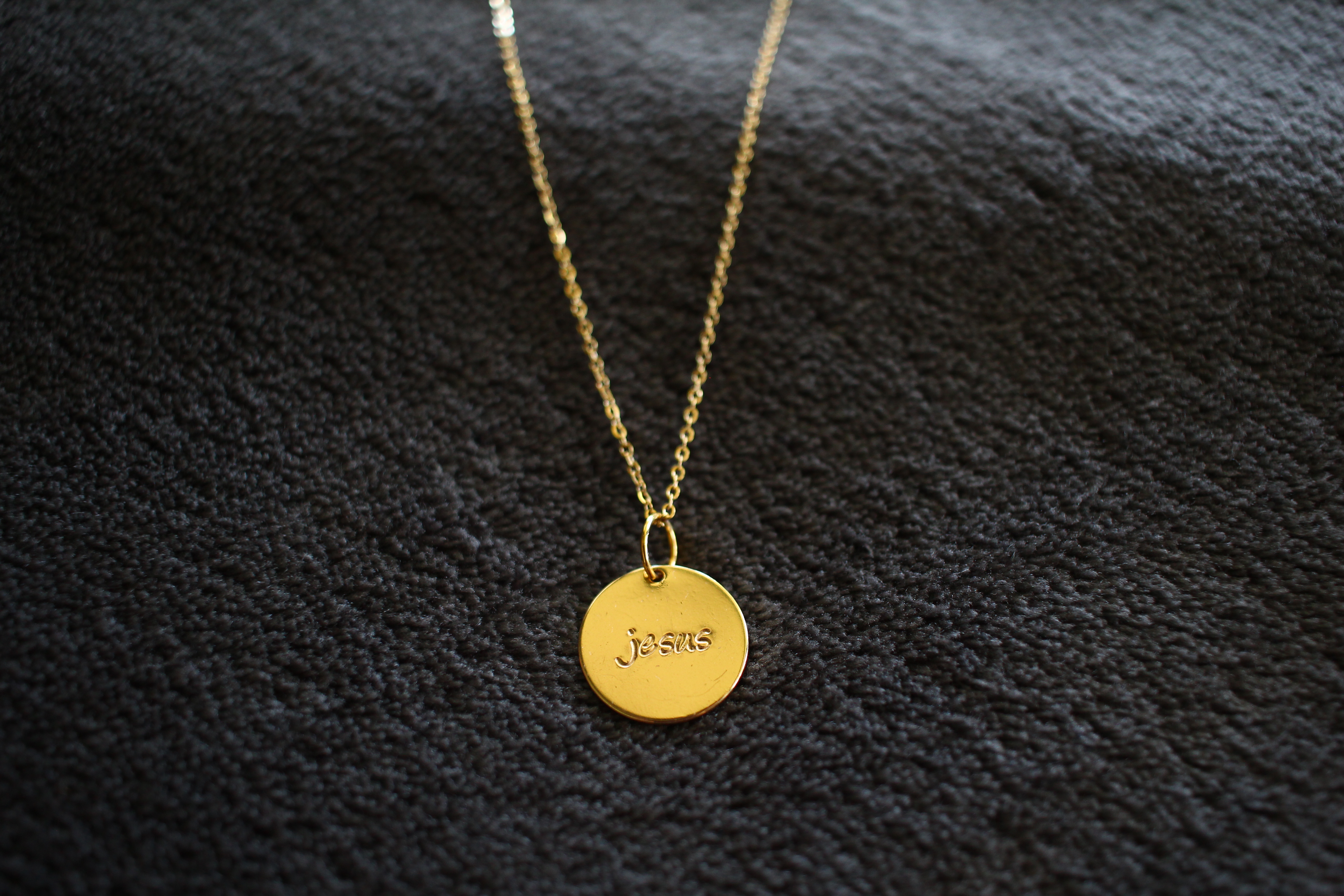 Gold necklace with 'Jesus' written on it